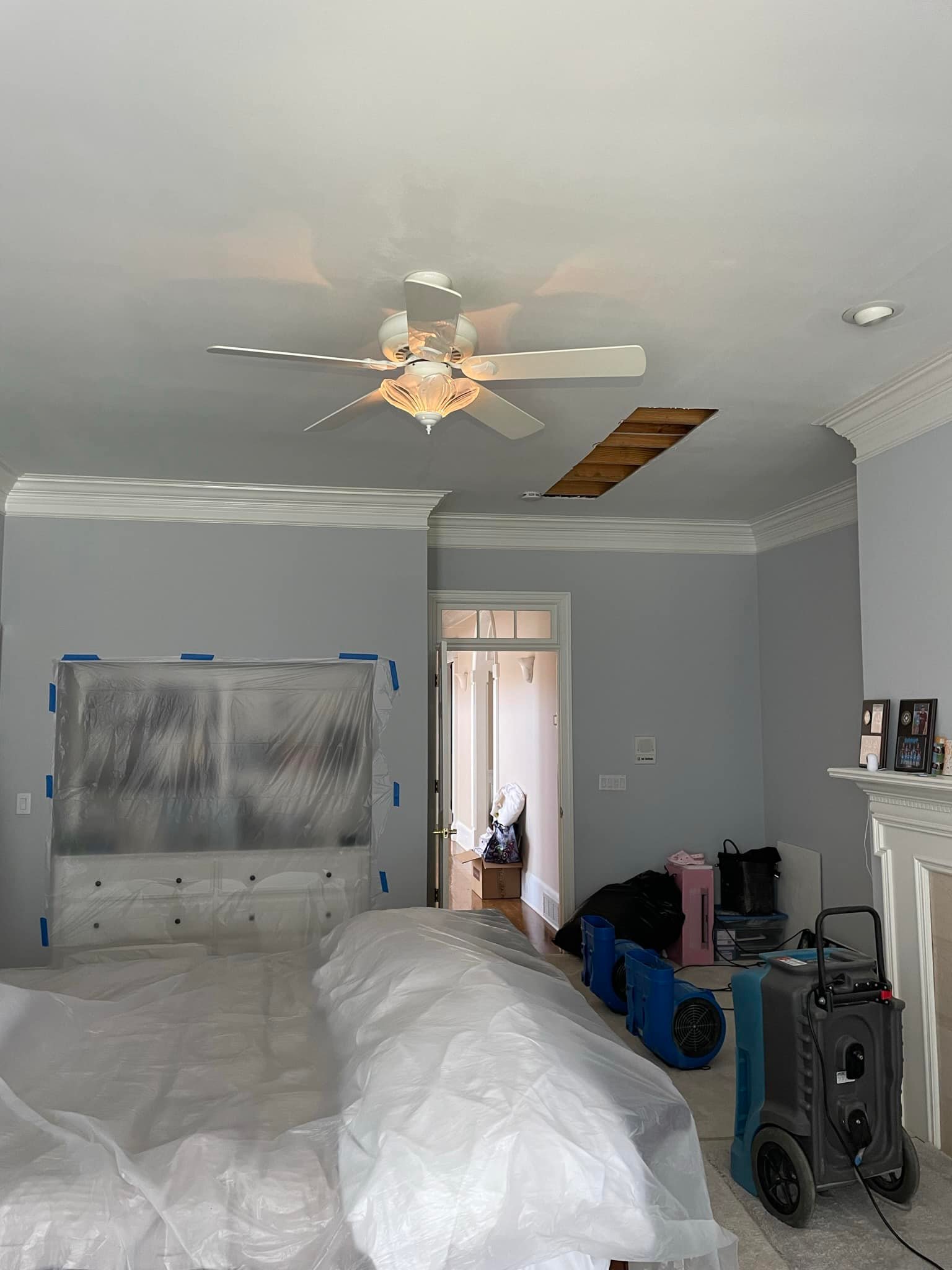 Bedroom with plastic containment barriers and dehumidification equipment during water damage restoration