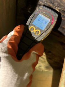 Property Restoration Pros technician taking a moisture meter reading during a water damage assessment