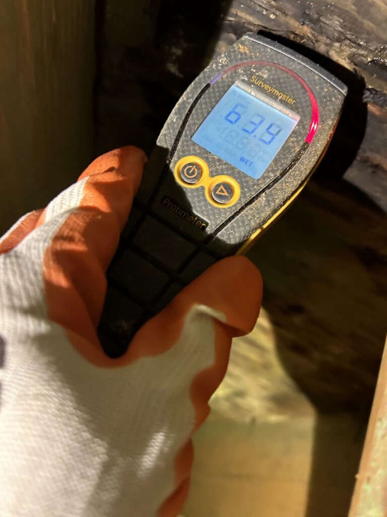 Property Restoration Pros technician taking a moisture meter reading during a water damage assessment